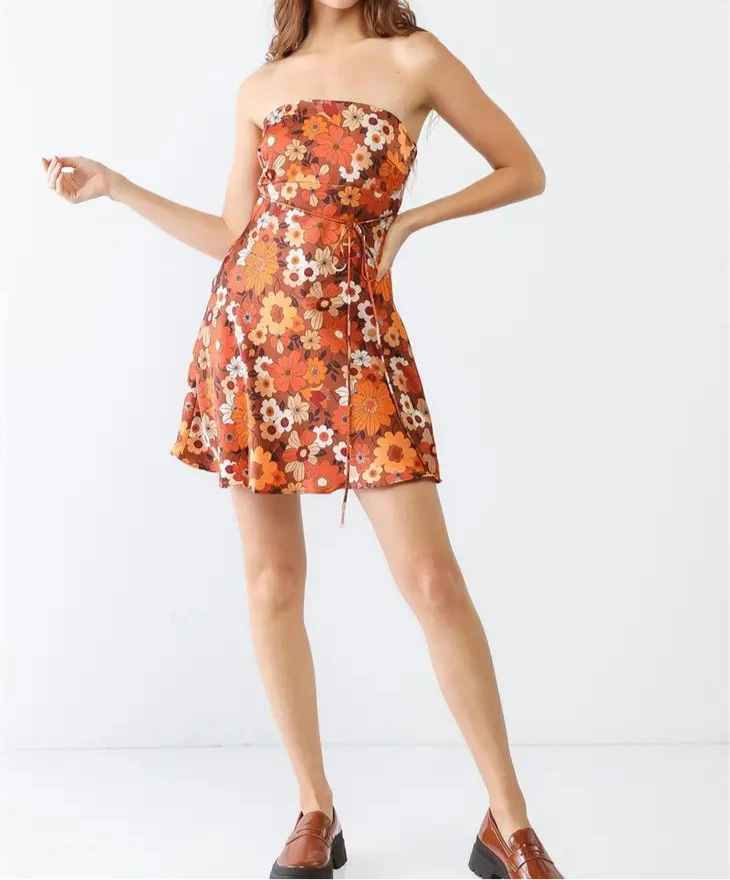 Woman wearing a strapless floral dress with orange and brown tones on a white background